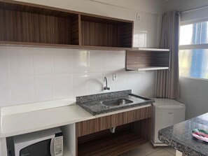 Una cocina moderna con baldosas blancas, armarios de madera, encimera de granito y lavavajillas integrado.