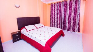 Une chambre à coucher avec un lit, une table de chevet et des rideaux.