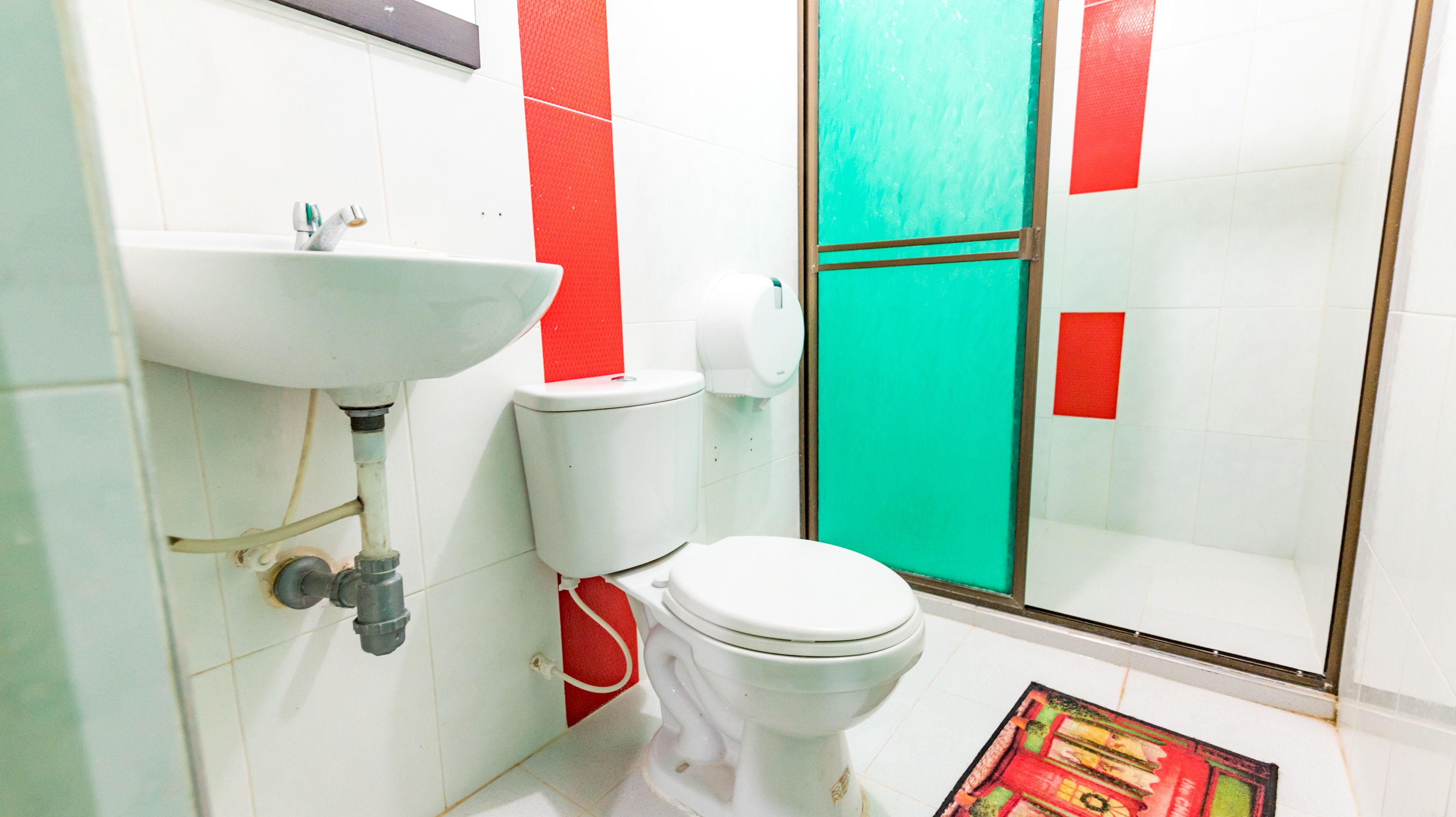 Un baño con lavamanos blanco, inodoro y puerta verde.
