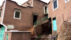 Un edificio tradicional con una escalera que conduce a un balcón, un letrero en idioma extranjero y una rústica pared de piedra.