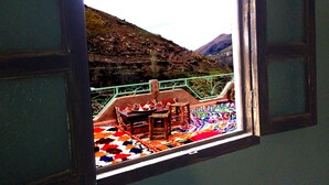 Habitación con vista a un paisaje montañoso a través de una ventana con barandilla de metal verde.