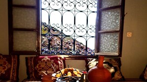 Una habitación con ventana, una bandeja con bebidas, un calentador de agua y un plato de comida.
