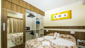 Habitación de hotel con cama, armario, espejo y una obra de arte colgada en la pared.