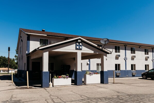 A building with a covered entrance, multiple windows, and air conditioning units.