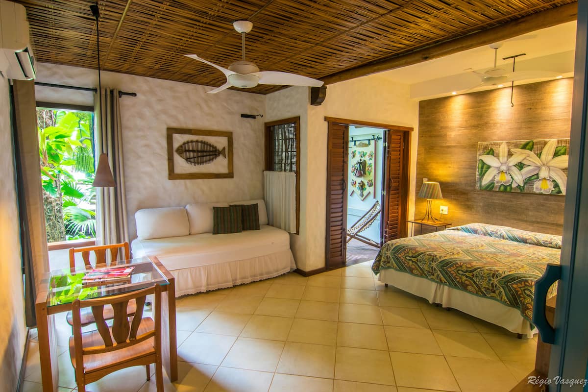 Una habitación con cama, sofá, mesa de comedor y ventilador de techo.