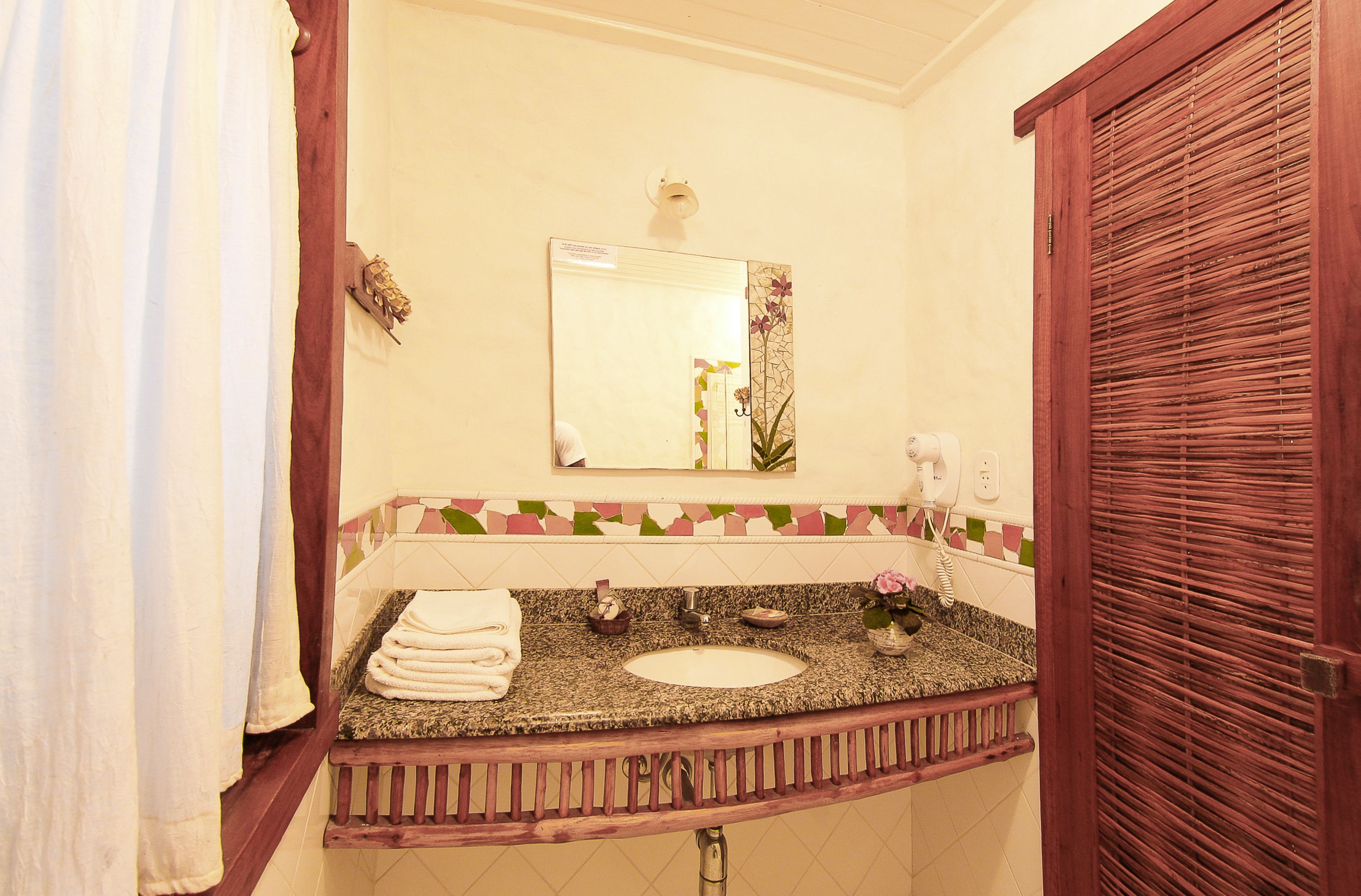 Un baño con lavamanos, espejo, toallero y puerta de madera.