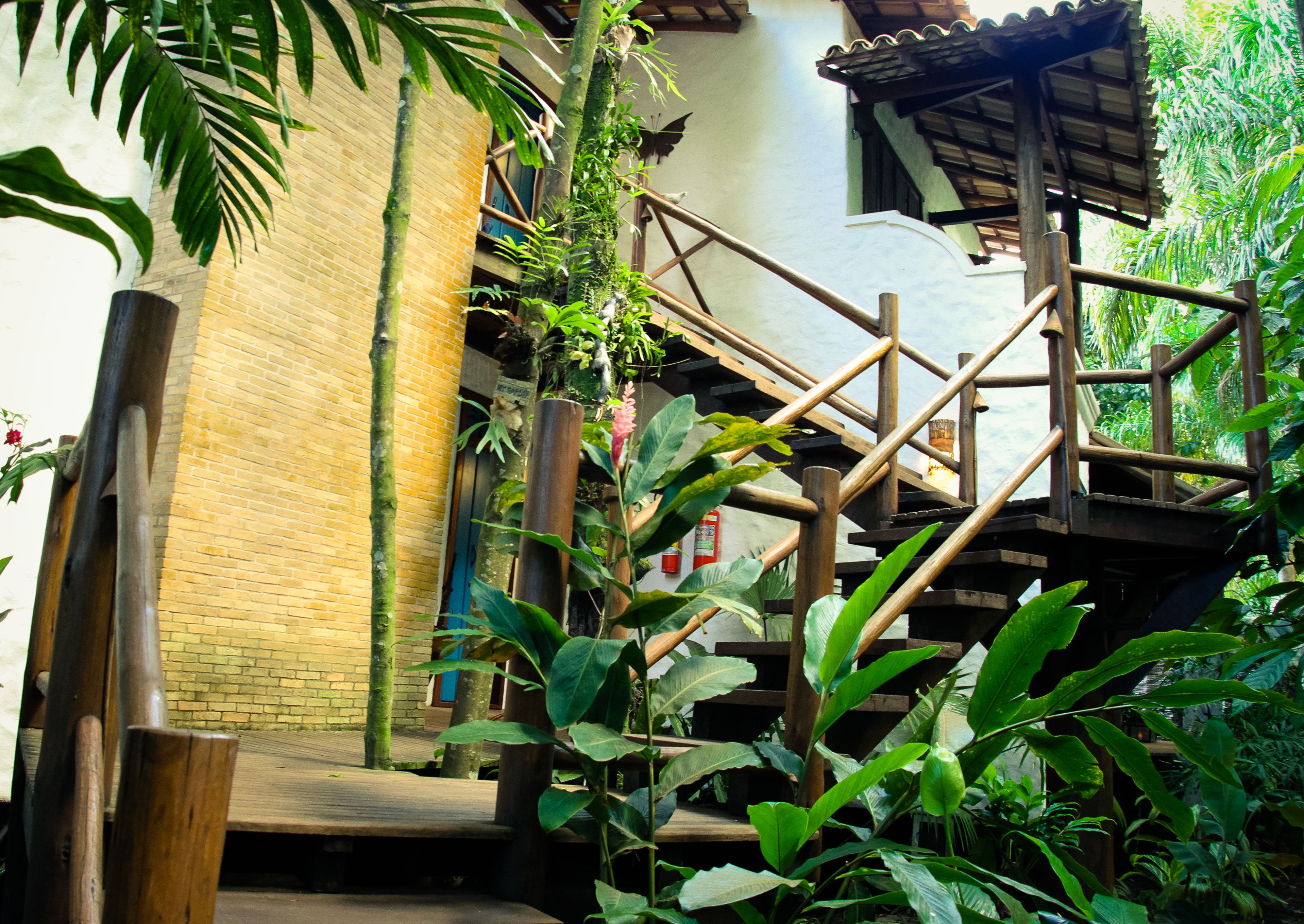 A wooden staircase with a brick wall and lush greenery.
