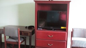 A wooden desk with a striped chair, a television on a cabinet, and a second striped chair. - Sportsman Motel (Eagle Lake)