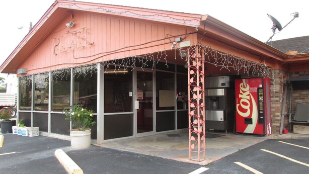 A building with a red exterior, large windows, and a Coca-Cola vending machine. - Sportsman Motel (Eagle Lake)