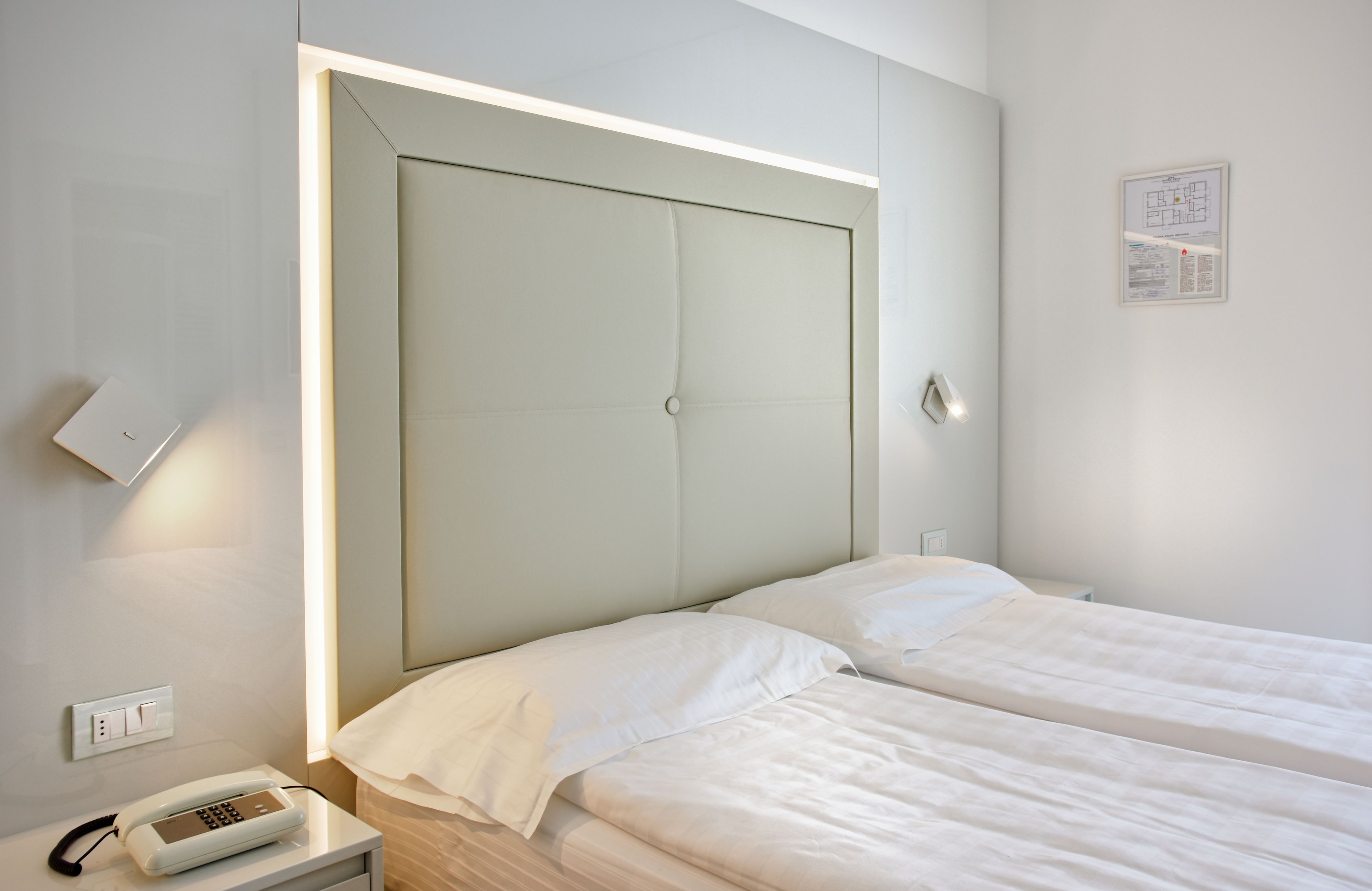 A hotel room with a large bed, bedside table, and a wall-mounted phone.