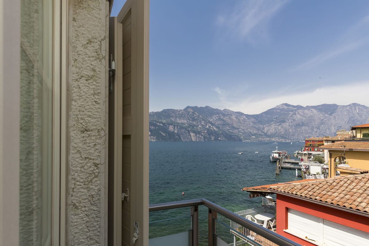 A balcony with a view of a calm sea and distant mountains.