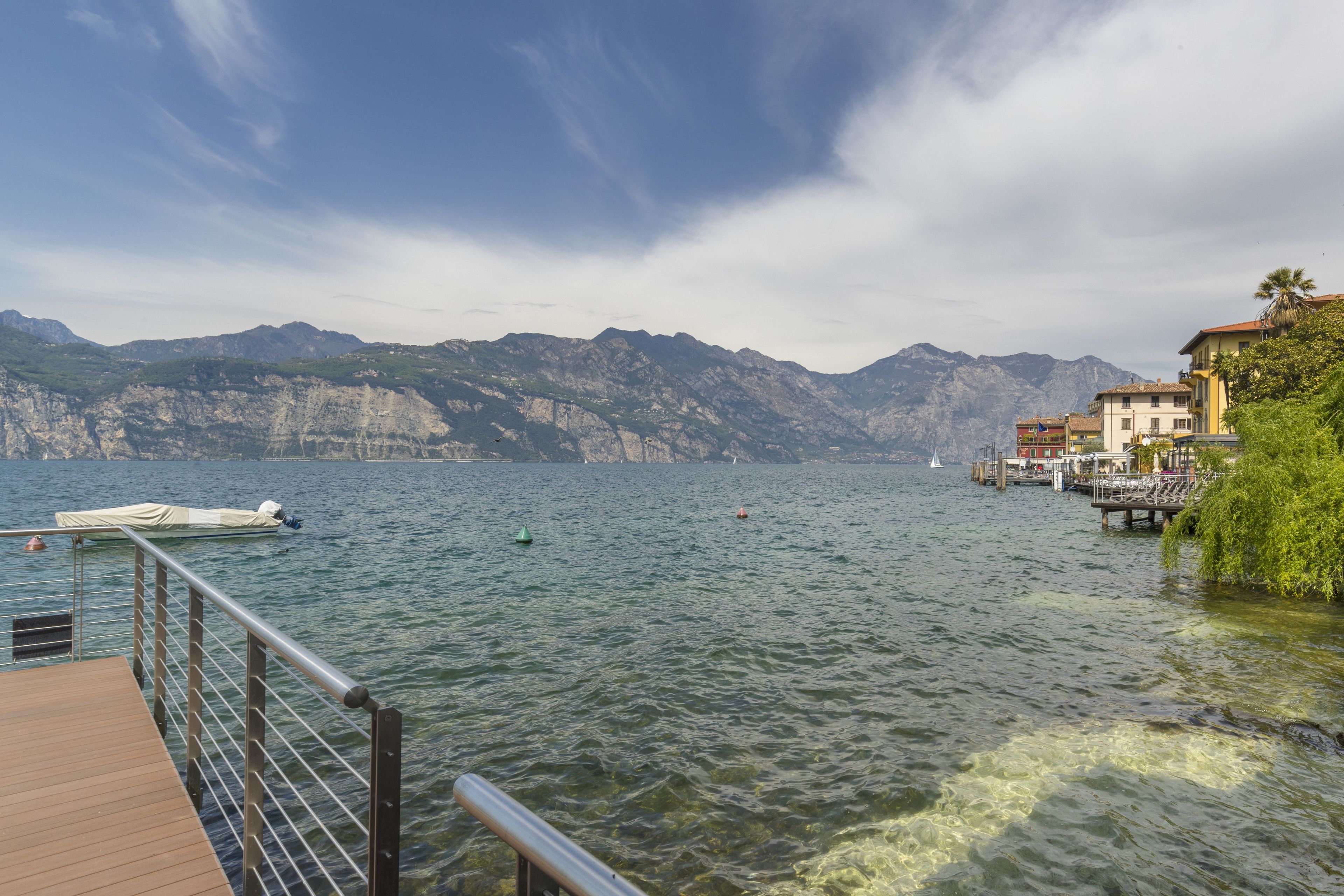 A lake with a wooden dock, boats, and buildings on the shore.