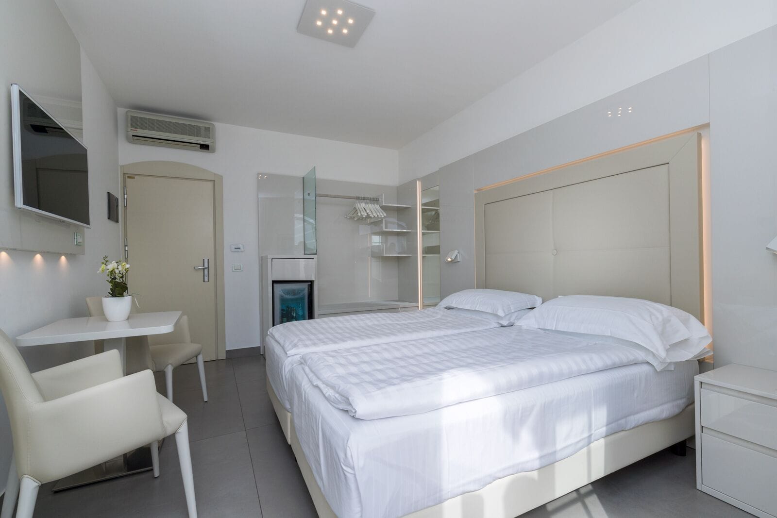 Ein modernes Hotelzimmer mit Bett, Nachttischen, einem Schreibtisch und einem Sessel.