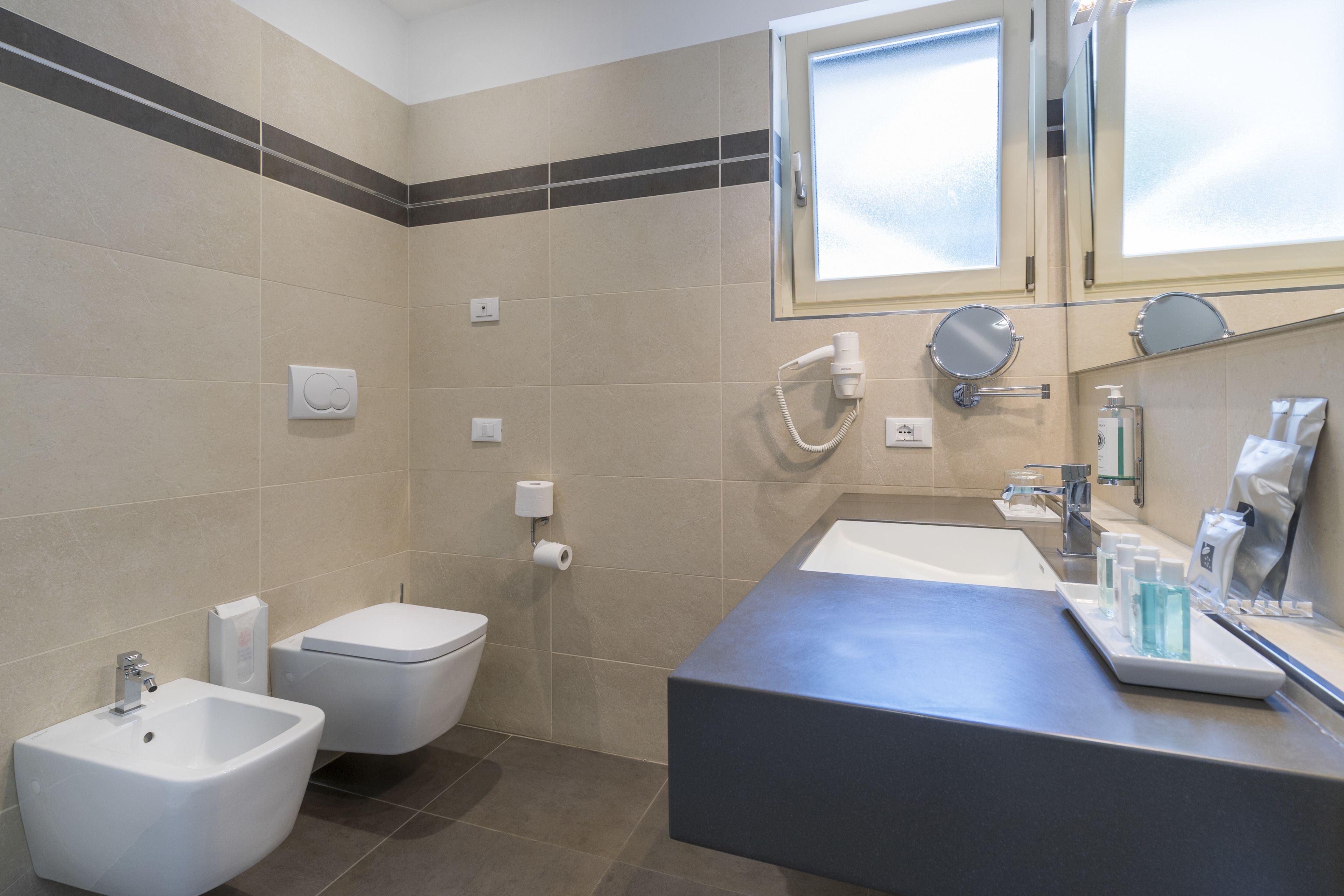 A modern bathroom with a bidet, toilet, and sink.