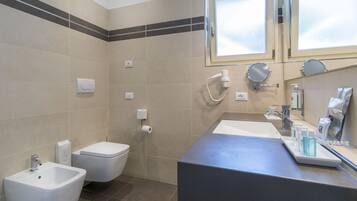 A modern bathroom with a bidet, toilet, and sink.