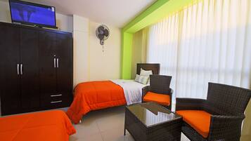 Ein Hotelzimmer mit einem Bett, einem Sessel, einem Tisch, einem Kleiderschrank und einem Fernseher.
