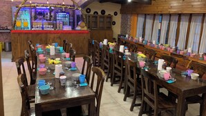 Un restaurant avec des tables et des chaises en bois, un coin bar avec un comptoir et un mur en pierre.