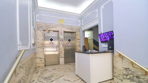 A marble-floored lobby with elevators, a reception desk, and a television screen. - MZ Apartments Prado I (Rio de Janeiro)