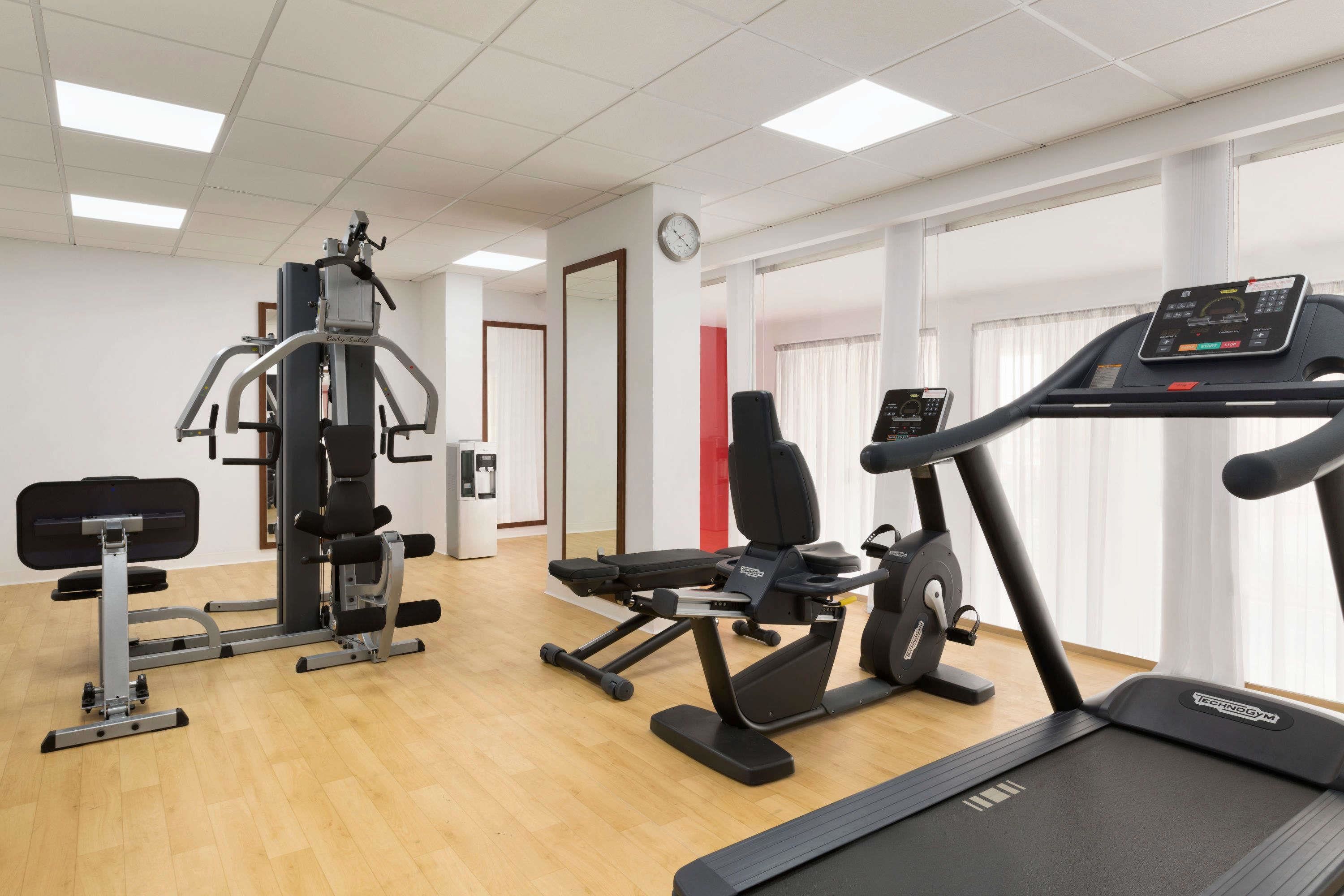 A gym with a treadmill, weight machines, and a bench.