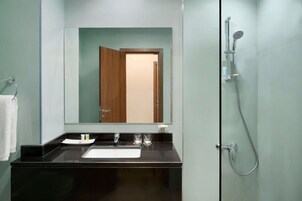 Un baño moderno con un lavamanos negro, espejo y ducha.