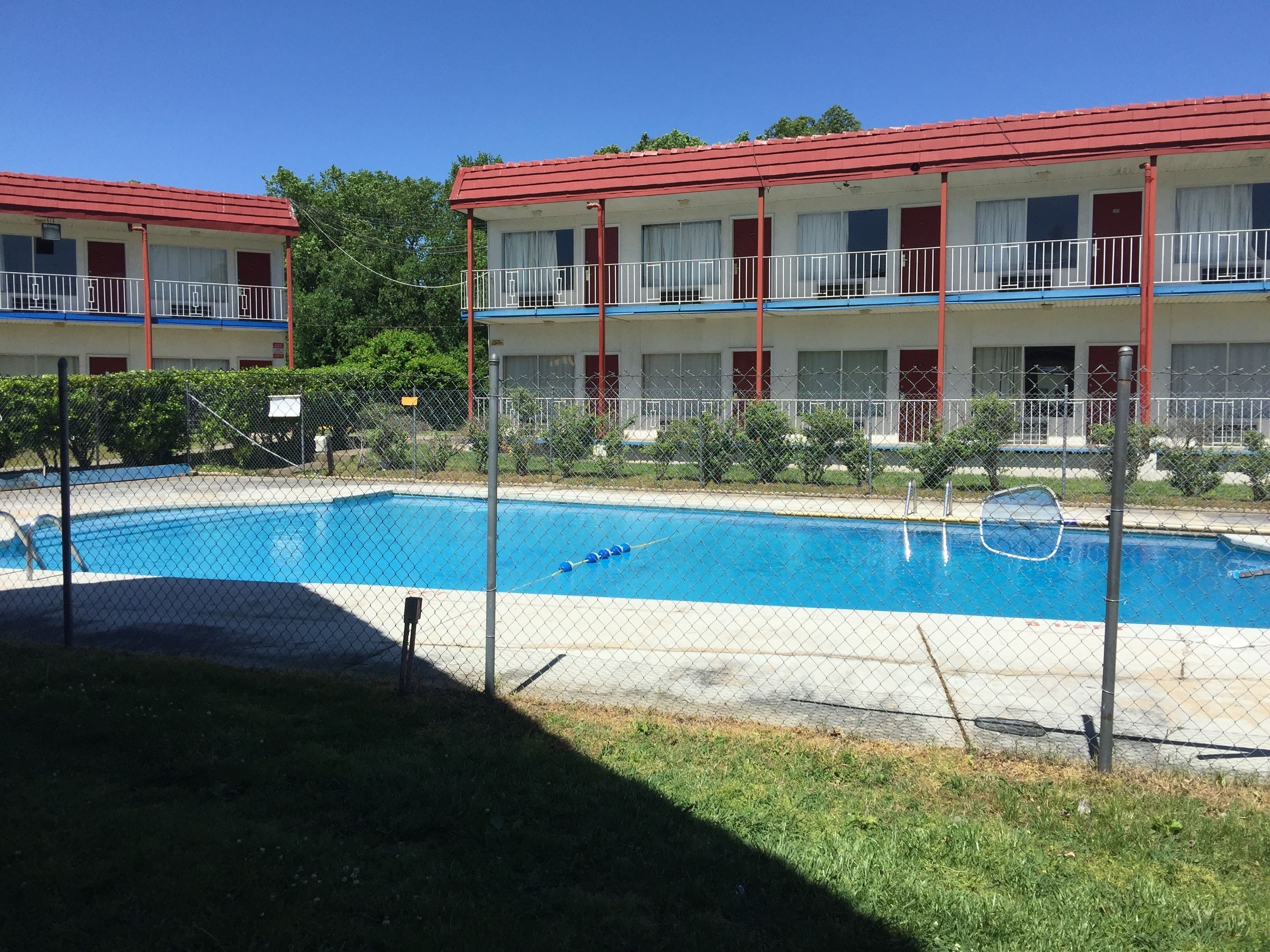 Un hotel con piscina, edificios de dos plantas y zona vallada.