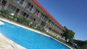 En swimmingpool med en byggnad med rött tak i bakgrunden.