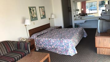 A hotel room with a bed, a sofa, a desk, and a kitchenette.