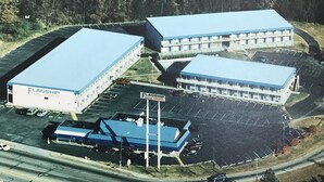 En vy från ovan av ett hotellkomplex med flera byggnader, en parkeringsplats och en flaggstång med skyltar.