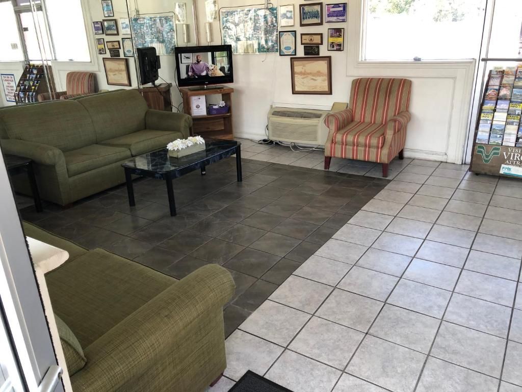 A living room with a sofa, armchair, and a coffee table. There is a television and a speaker in the room.