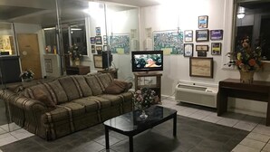Ett vardagsrum med en soffa, ett soffbord, en tv och en vägg som är dekorerad med inramade bilder och en anslagstavla.