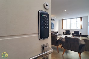 A modern hotel room with a digital door lock, a conference table, and comfortable seating.