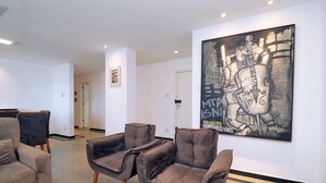A modern interior with two brown armchairs, a green table, and a large abstract painting on the wall. - MZ Apartments Prado Junior (Rio de Janeiro)