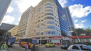 A multi-story building with a curved facade, several windows, and a visible storefront with signage. - MZ Apartments Prado Junior (Rio de Janeiro)