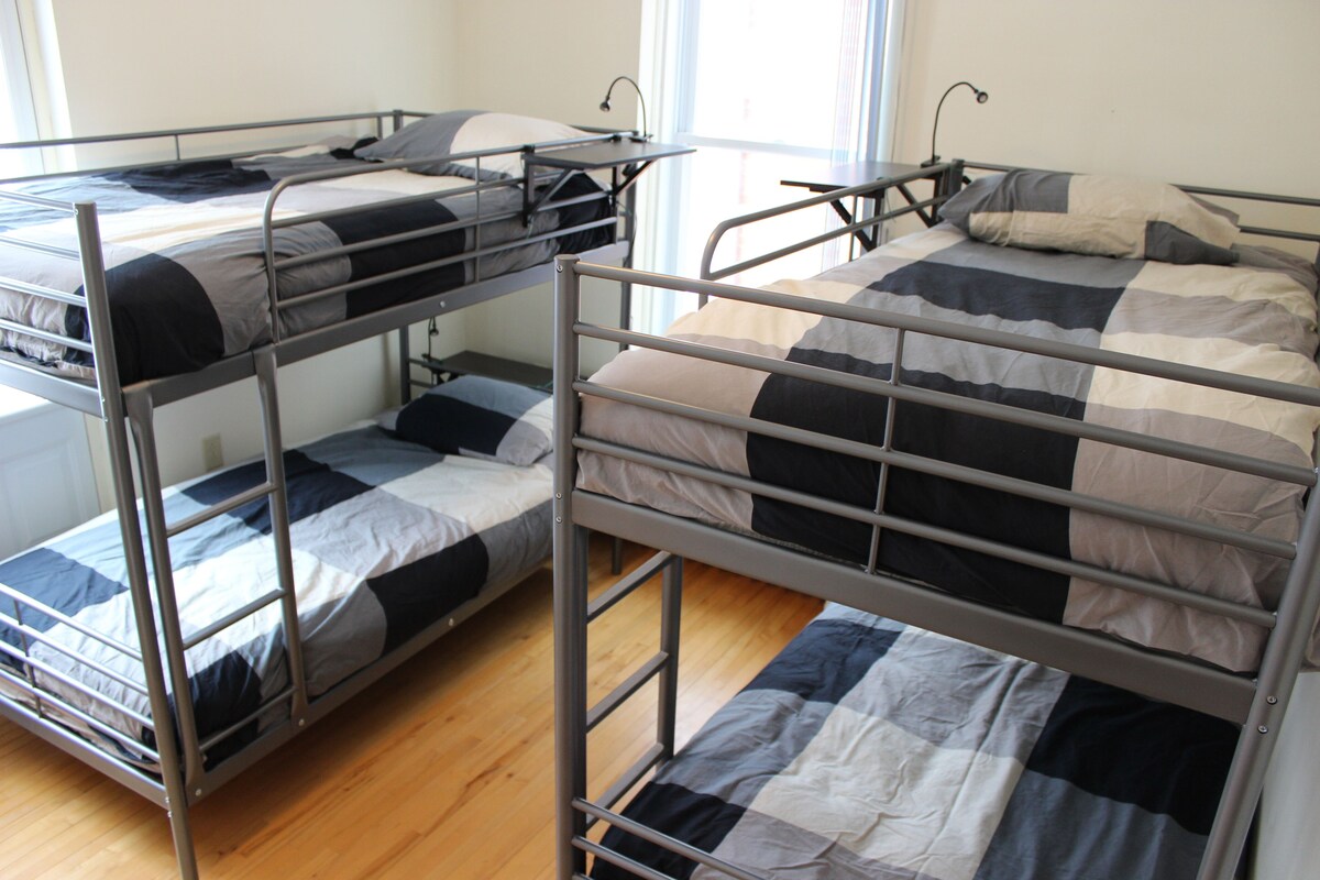 A room with three bunk beds, each with a metal frame and a checkered bedspread.