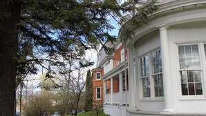 A traditional two-story house with a white exterior, a front porch, and a brick facade. - Auberge Jeunesse Magog-Orford (Hostel) (Magog)