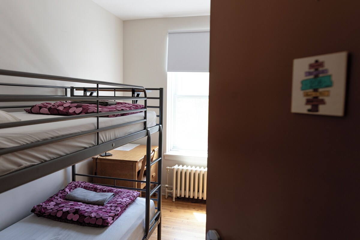 A bunk bed room with a wooden desk and a radiator.