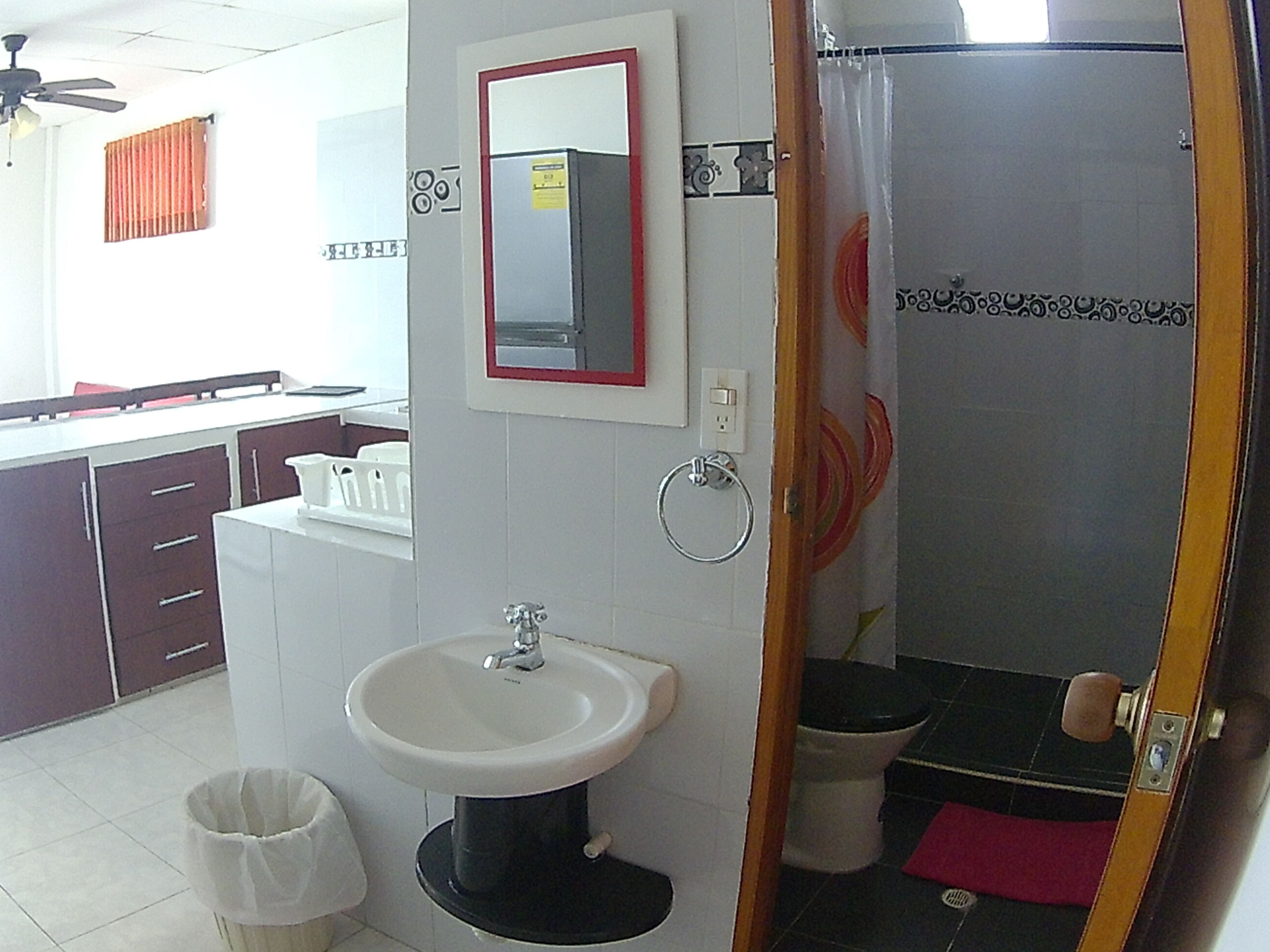 A bathroom with a sink, mirror, toilet, and shower curtain.