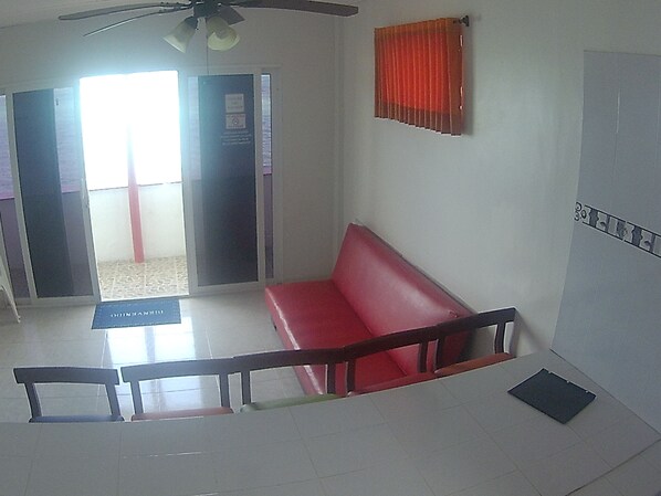 A reception area with a red bench, a glass door entrance, and a ceiling fan. - Rocky Cay Bay (San Andrés)