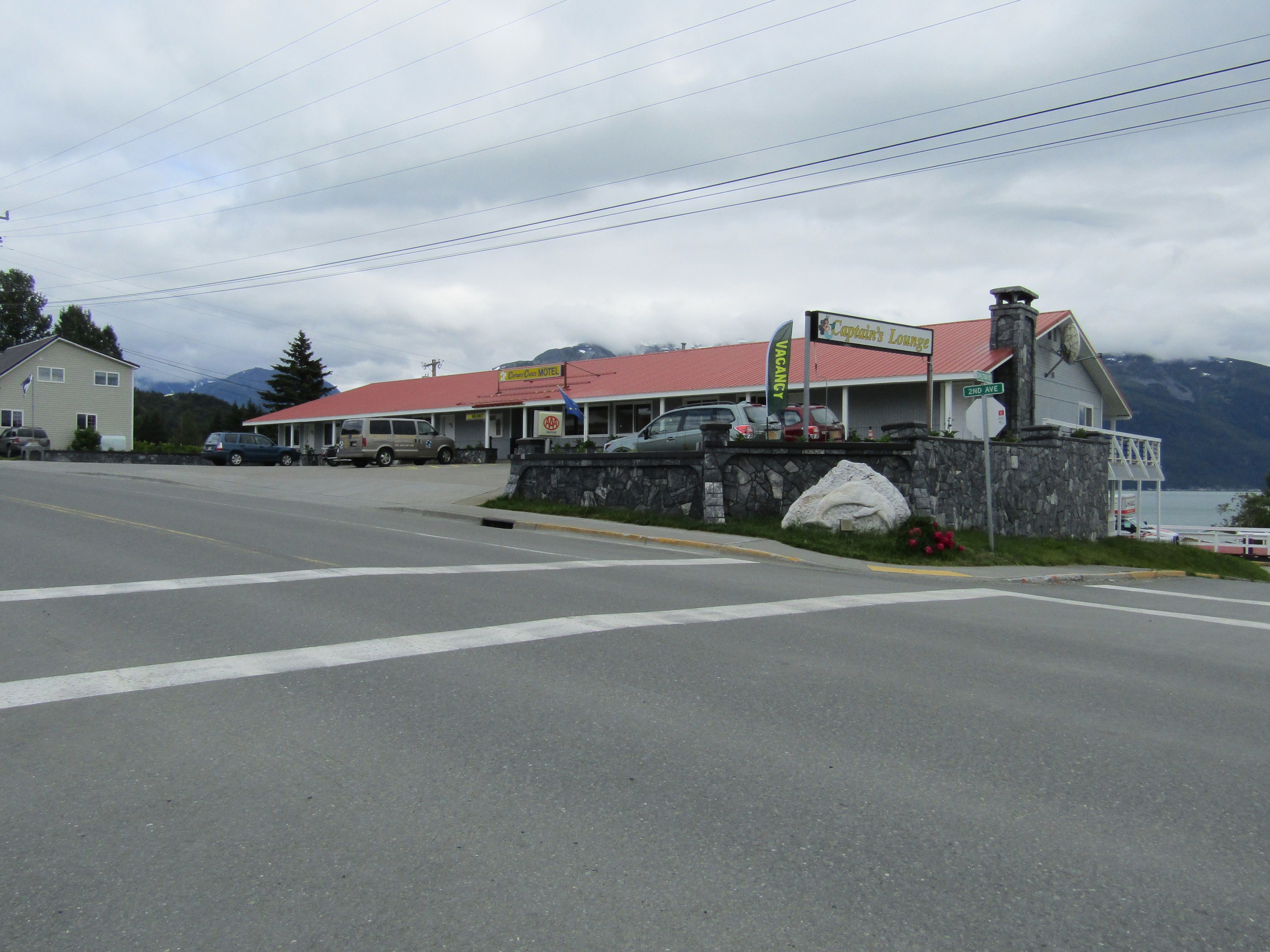 A motel with a red roof, a stone wall, and a sign for Captain's Lounge.
