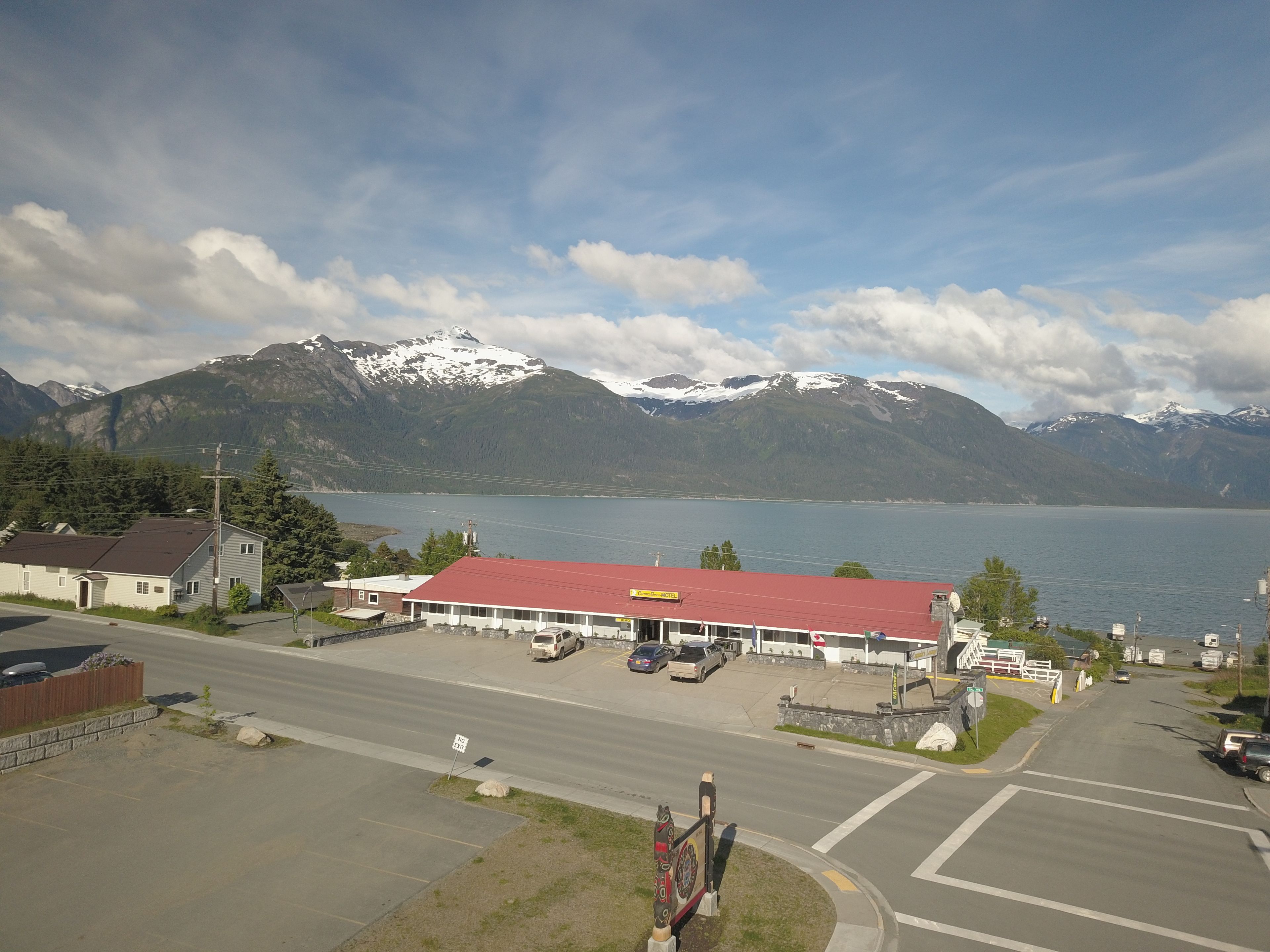 A hotel with a red roof, a parking lot, and a view of mountains and a lake.