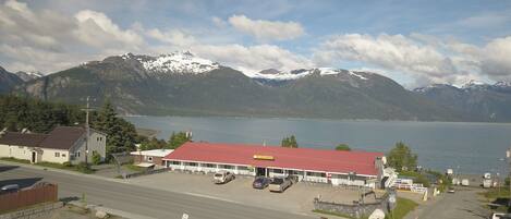 A hotel with a red roof, a parking lot, and a view of mountains and a lake.