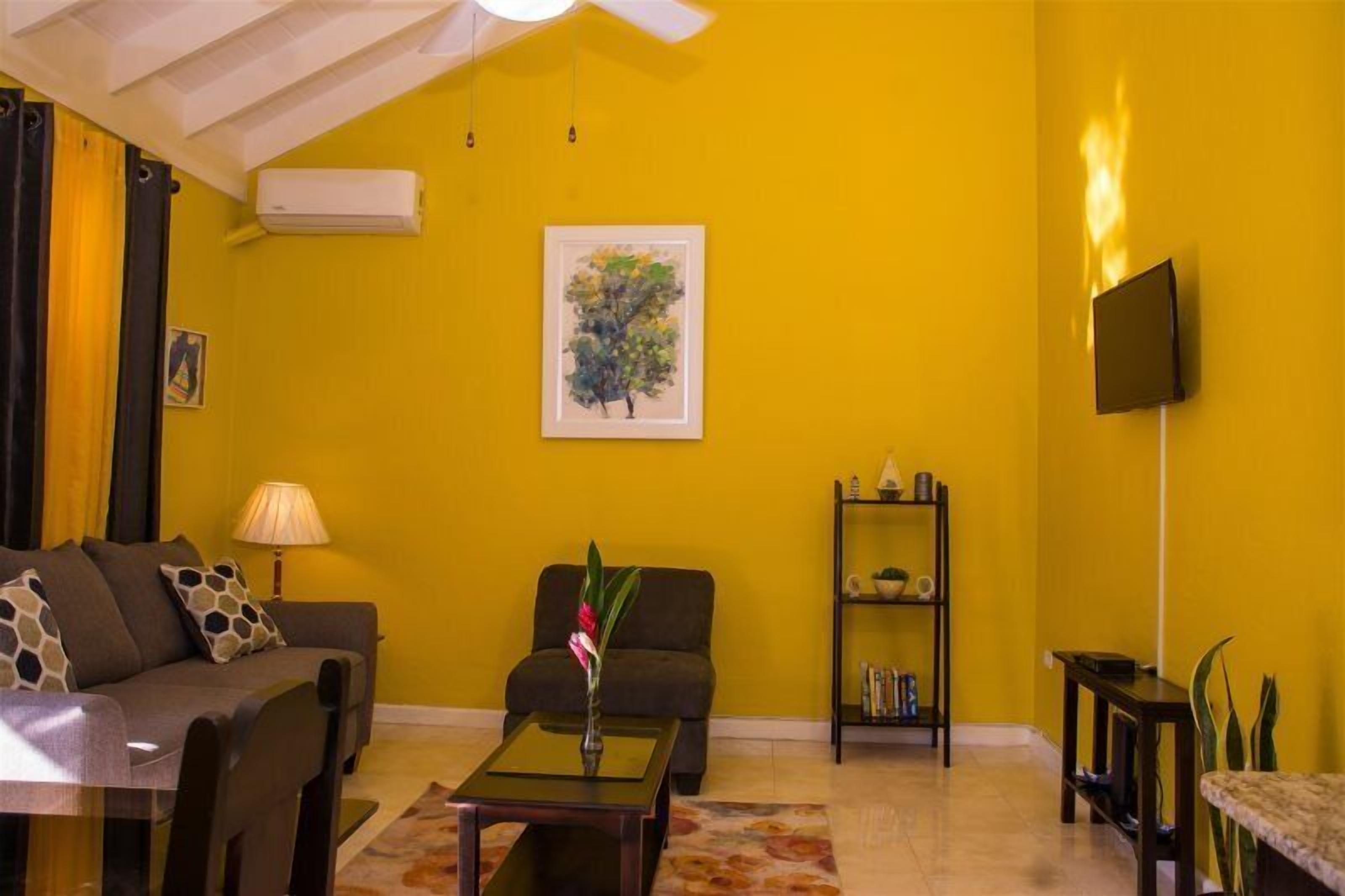 A living room with a yellow wall, a sofa, a coffee table, and a bookshelf.