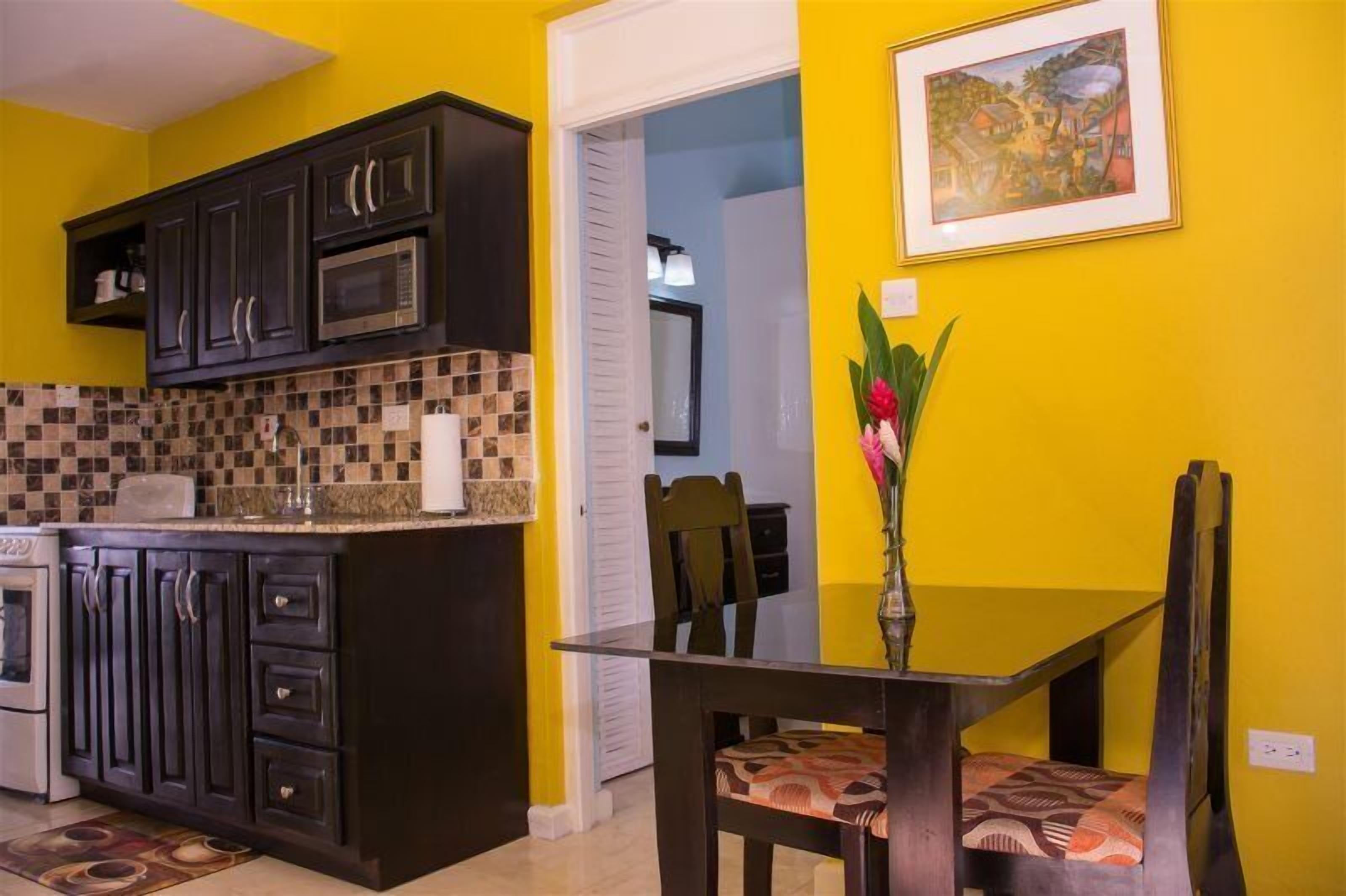 Une cuisine avec des meubles de couleur sombre, un four à micro-ondes et un dosseret carrelé.