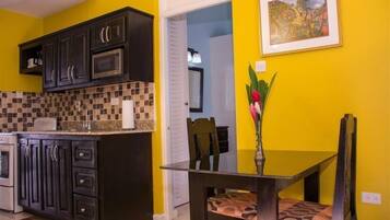 A kitchen with dark cabinets, a microwave, and a tiled backsplash.