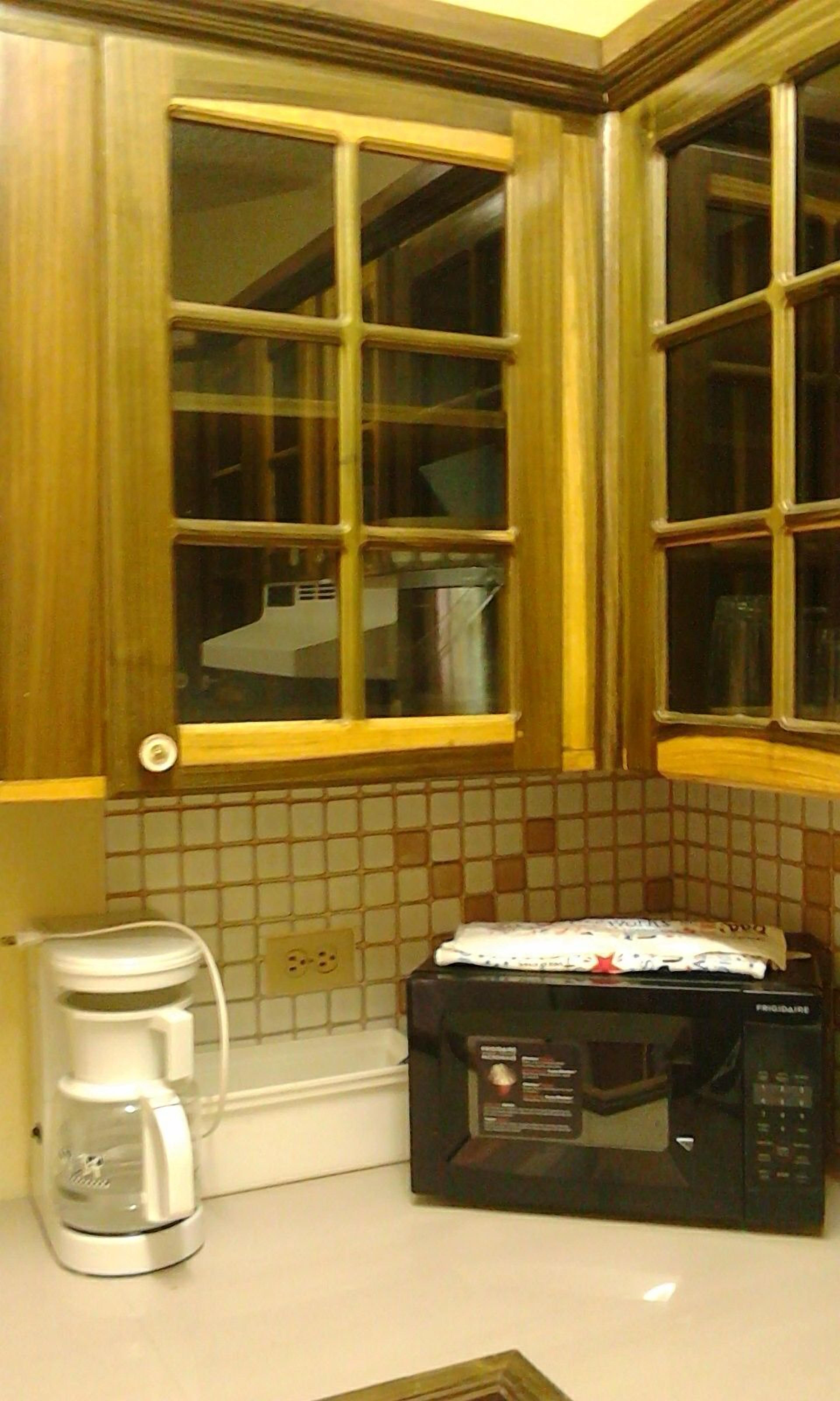 A kitchen with wooden cabinets, a window, a coffee maker, and a microwave.