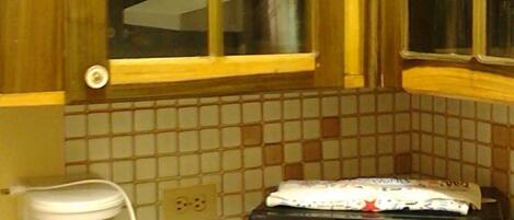 A kitchen with wooden cabinets, a window, a coffee maker, and a microwave.