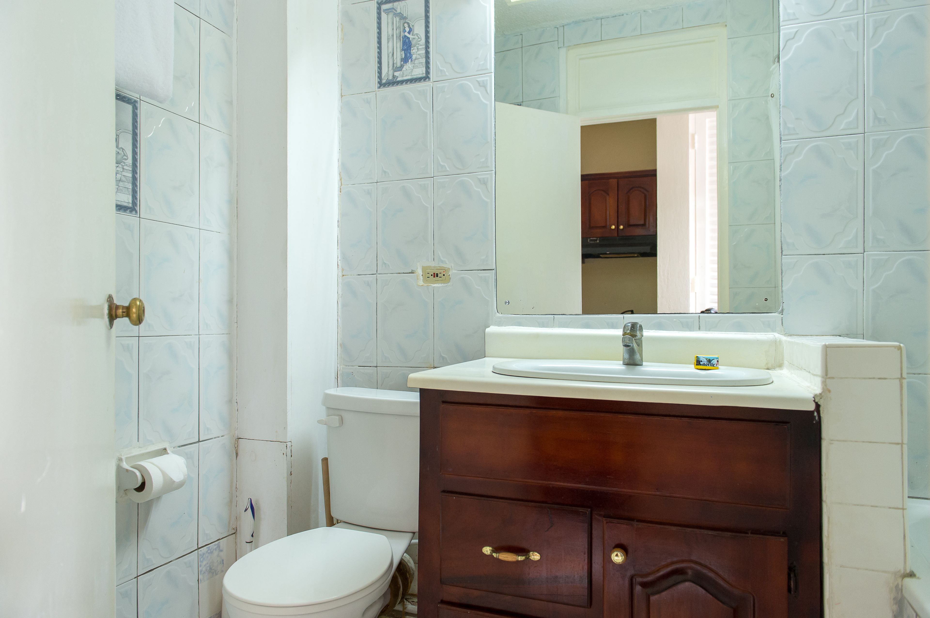 A bathroom with a toilet, sink, and mirror.