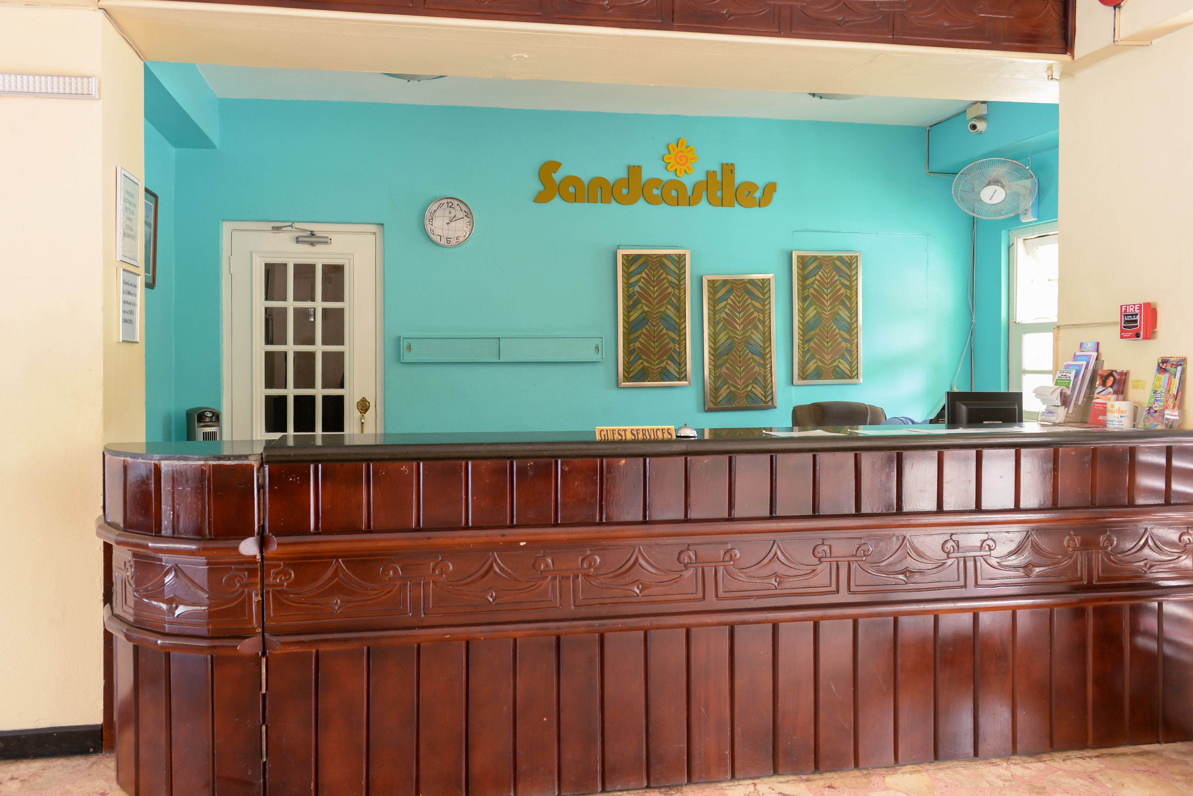 A reception desk with a clock, framed artwork, and a sign reading "Sandcastles".