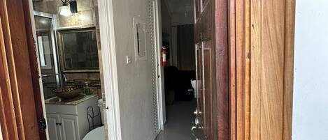 A hallway with a wooden door, a white toilet, and a sink with a bowl.