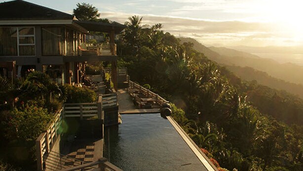 Un resort con piscina, terraza de madera y abundante vegetación.
